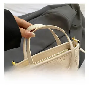 Detailansicht der beigen Tasche mit Katzenmuster, Goldreißverschluss und Ledertextur