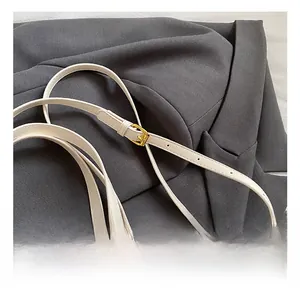 Détail de la bandoulière réglable en cuir blanc avec boucle dorée et imprimé fraise