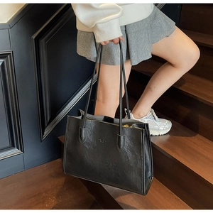 Detail of a black textured tote bag with double handles on a wooden staircase