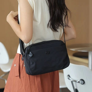 Close-up of lightweight nylon crossbody bag showing the adjustable strap and logo detail