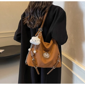 Dettaglio borsa tote vintage caramello con logo in metallo e charm a nuvola morbida