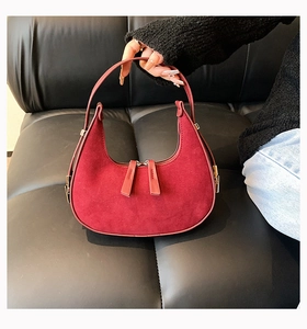 Detailed close-up of wine red suede hobo bag with dual gold zippers and smooth handle