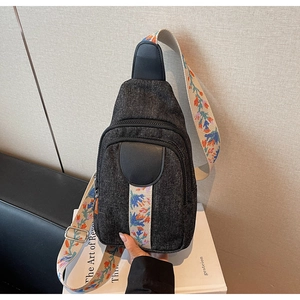 Close-up of durable black denim chest bag featuring vibrant floral embroidered shoulder strap