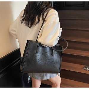 Detail of black tote bag featuring retro pleated leather texture and Fashion Trend lettering
