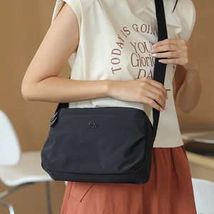 Detail of black nylon crossbody bag with metal logo and adjustable wide strap