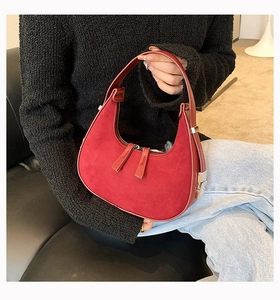 Detail of red suede hobo bag with contrast leather trim and silver metal side buckles