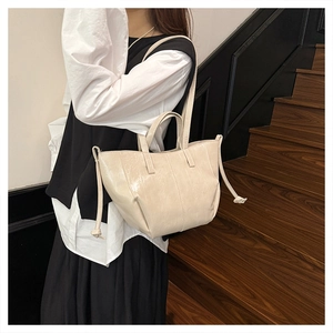Detail of a cream faux leather tote bag showing smooth oil-skin texture and side knots