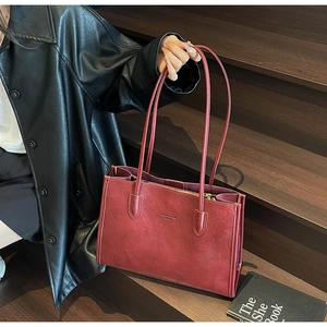 Close-up of burgundy faux leather tote bag with zipper and shoulder strap on wooden stairs