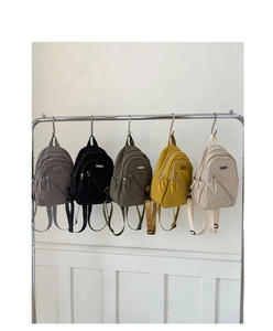 Detail of five stylish mini backpacks in various colors hanging on a metal display rack