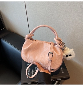Pink pleated cloud bag with metallic details and cute plush charm on design books