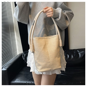Detail of woven bucket bag with cream tubular handle and silver metal adjustment buckle