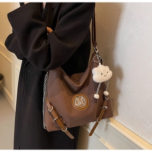 Dettaglio della borsa hobo marrone vintage con logo M in metallo e ciondolo a nuvola