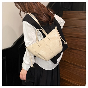 Model wearing a vintage beige tote bag with a long shoulder strap and knot details