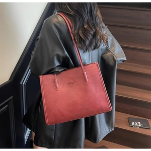 Close-up of a red tote bag with retro wrinkled texture and fashion trend logo on a model