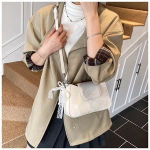 Detail of cream white leather shoulder bag with delicate lace pearl bow accessory