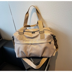 Dettaglio della grande borsa da viaggio kaki con tracolla regolabile su sedia in pelle