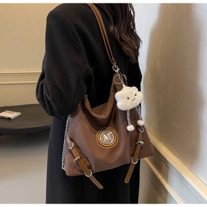 Dettaglio della borsa tote marrone con logo M, catena e ciondolo a nuvola bianca