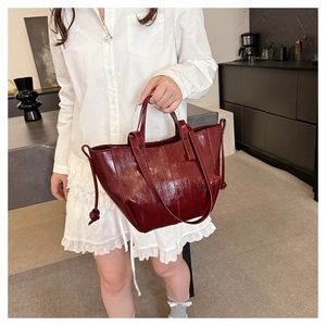 Detail of burgundy glossy faux leather tote bag showing textured finish and drawstring nodes