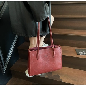 Detailed view of burgundy tote bag with fine textured faux leather on dark wooden stairs