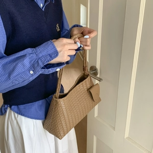 Dettaglio di borsa a mano intrecciata marrone con mini pochette abbinata in omaggio