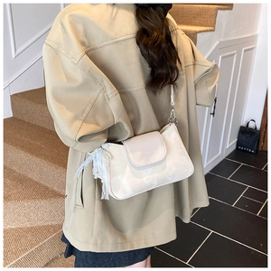Detailed shot of cream white faux leather shoulder bag with lace and pearl charm