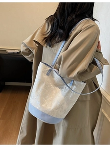 Floral canvas bucket tote bag with blue trim shown on a model in a minimal interior