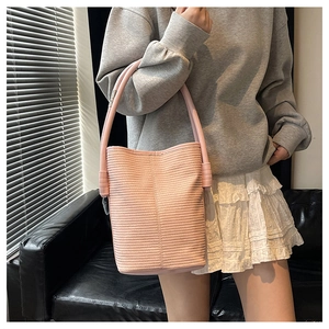Detailed view of a pink woven bucket handbag featuring a thick handle and textured finish
