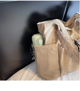 Detail of the tote bag side pocket with adjustable drawstring holding a water bottle