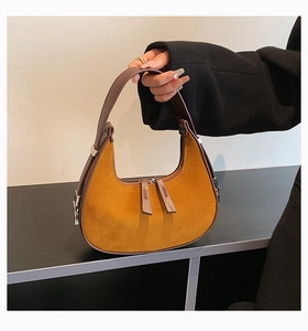 Detail of amber suede hobo bag with dark brown trim and silver metal hardware