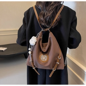 Dettaglio zaino in nylon color caffè con logo M in metallo e accessorio pendente in peluche