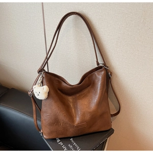 Close-up of brown vintage tote bag with soft lychee texture and cute bear charm