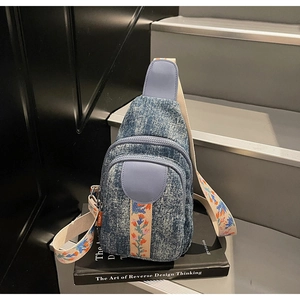 Detail of vintage denim crossbody bag with floral embroidered strap on a book