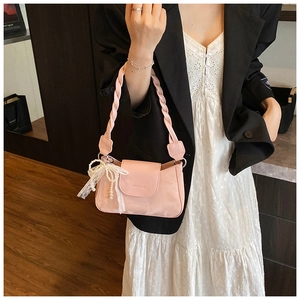 Detail of pink faux leather underarm bag with woven handle and lace pearl bow charm