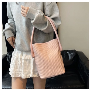 Detail of pink woven bucket bag with textured pattern and cylindrical handle