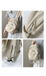 Detail view of beige nylon crossbody chest bag showing zippers, buckle and textured fabric