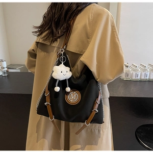 Dettaglio della borsa in nylon nero con cinturini in pelle, catene e ciondolo a nuvola