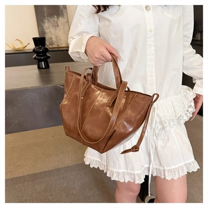 Detail of vintage brown leather tote bag with glossy finish and long shoulder straps