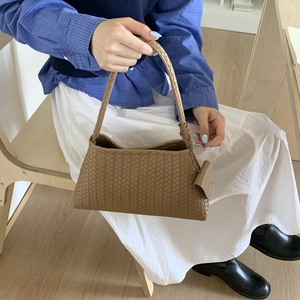 Dettaglio della borsa a spalla in pelle intrecciata marrone con mini ciondolo a busta
