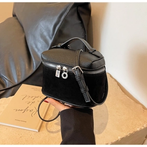 Detail of black pebbled leather mini box bag with silver zippers and elegant suede panel