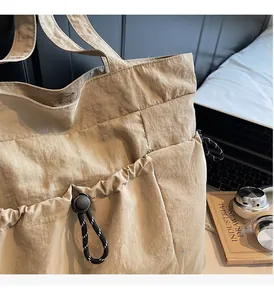 Detailed view of the side drawstring pocket and texture on a beige commuter tote bag