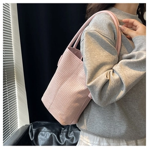 Pink woven tote bag featuring a horizontal textured surface worn on the shoulder