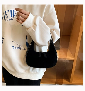 Detail of a black matte crescent hobo bag shown being worn by a model in a casual outfit
