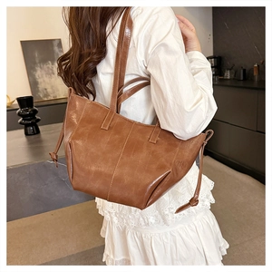 Brown large-capacity PU leather tote bag styled with white lace dress for a casual look