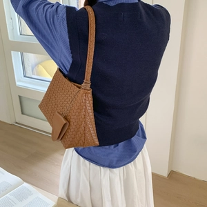 Dettaglio di una borsa a tracolla in pelle marrone intrecciata con lavorazione artigianale