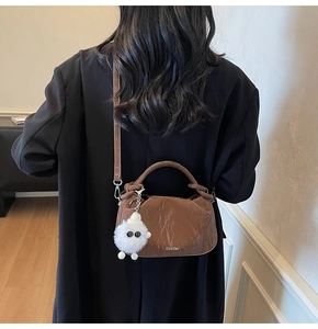 Close-up of coffee brown ruched leather bag with braided handle and fuzzy monster charm