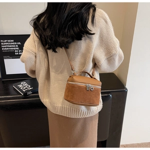 Model showcasing a bicolor leather cylinder bag with a top handle and shoulder strap