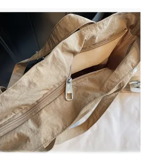 Detail of smooth silver metal zipper on khaki nylon tote bag showing internal storage
