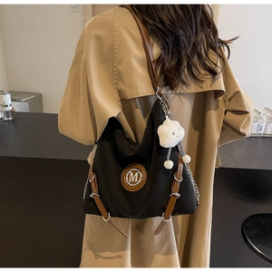 Dettaglio borsa tote vintage nera con finiture in pelle marrone e ciondolo di peluche