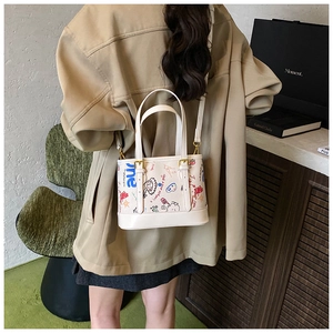 Détail du sac cabas en cuir blanc avec motifs graffiti colorés et finitions dorées