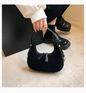 Detail of black crescent hobo bag featuring matte suede texture and smooth leather handle